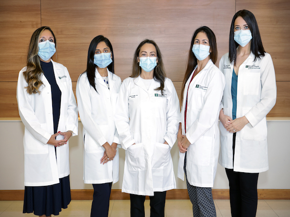 5 physicians wearing face masks and uniform stand for a photo.