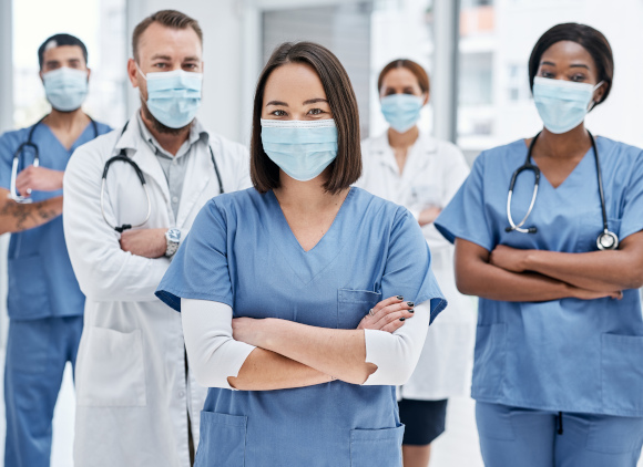 Four healthcare professionals communicating in a hallway